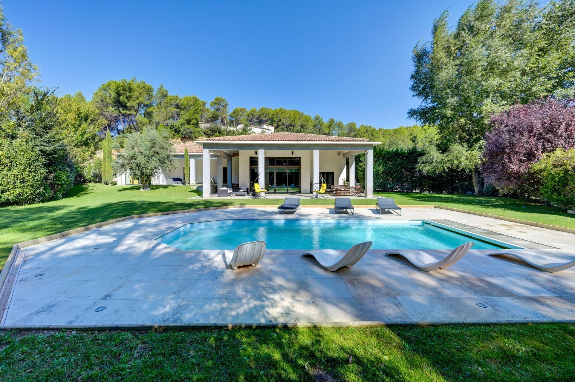 Piscine privée entourée de transats et de verdure